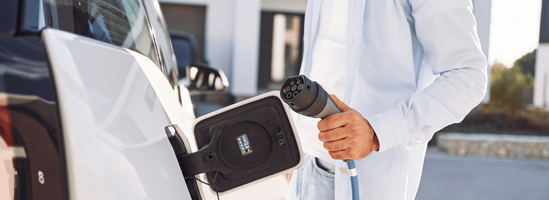 Mann lädt ein E-Auto auf