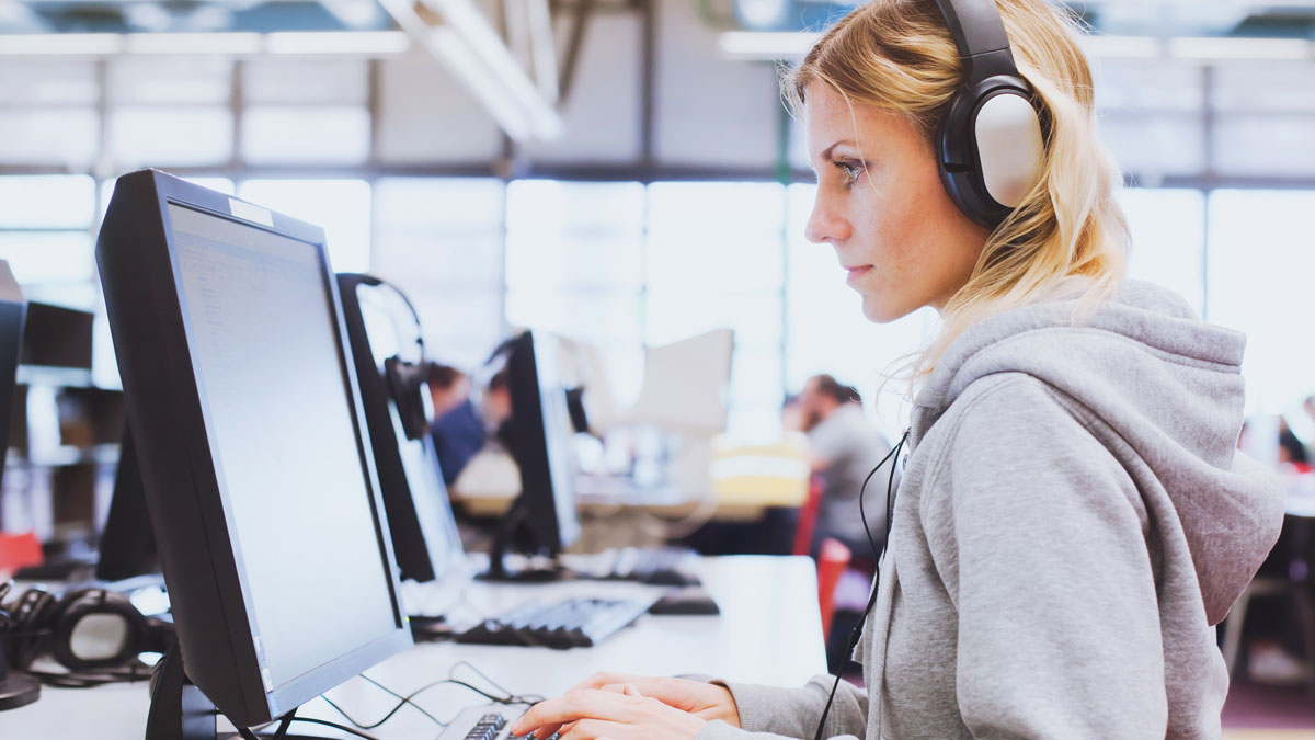 Junge Frau mit Headseat vor dem PC.