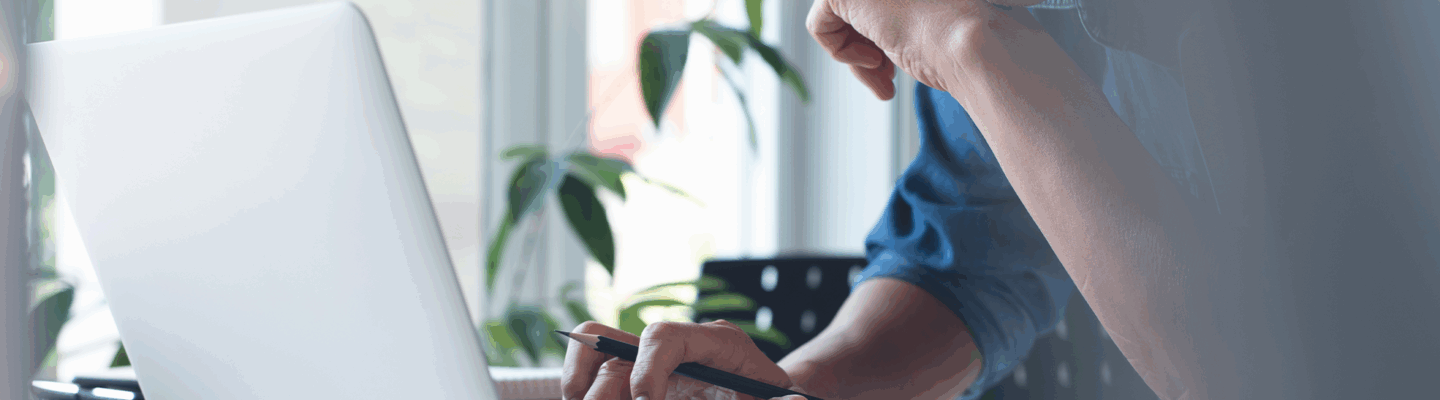 Mann sitzt vor einem Laptop, eine Hand ist auf der Tastatur.