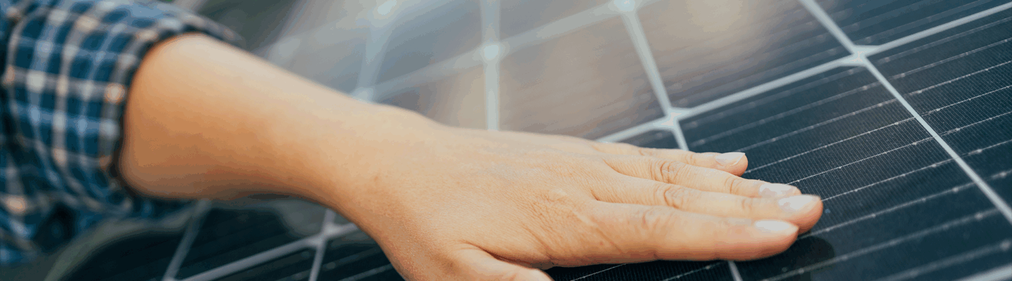 Eine Hand, die auf einem Solarpanel liegt