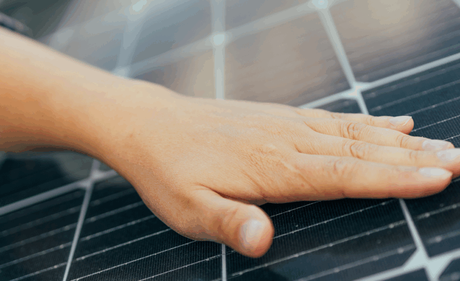 Eine Hand, die auf einem Solarpanel liegt