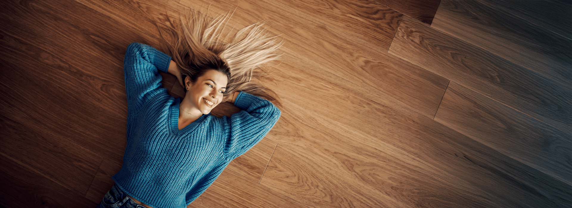 Frau liegt entspannt auf einem Holzboden