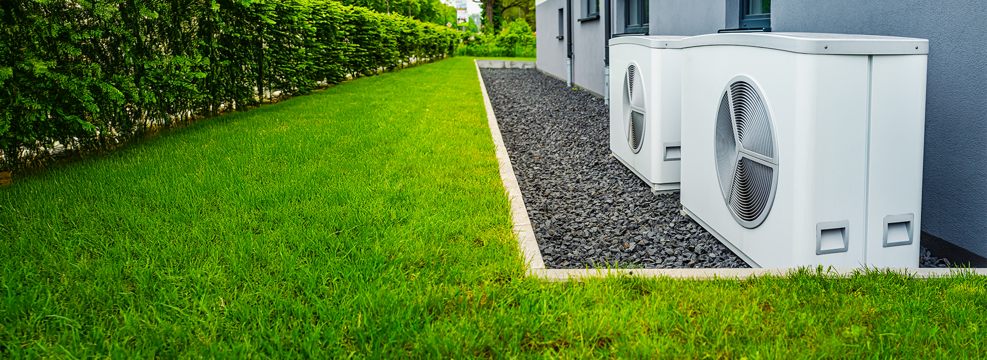 Wärmepumpen an einer Hauswand in einem Garten