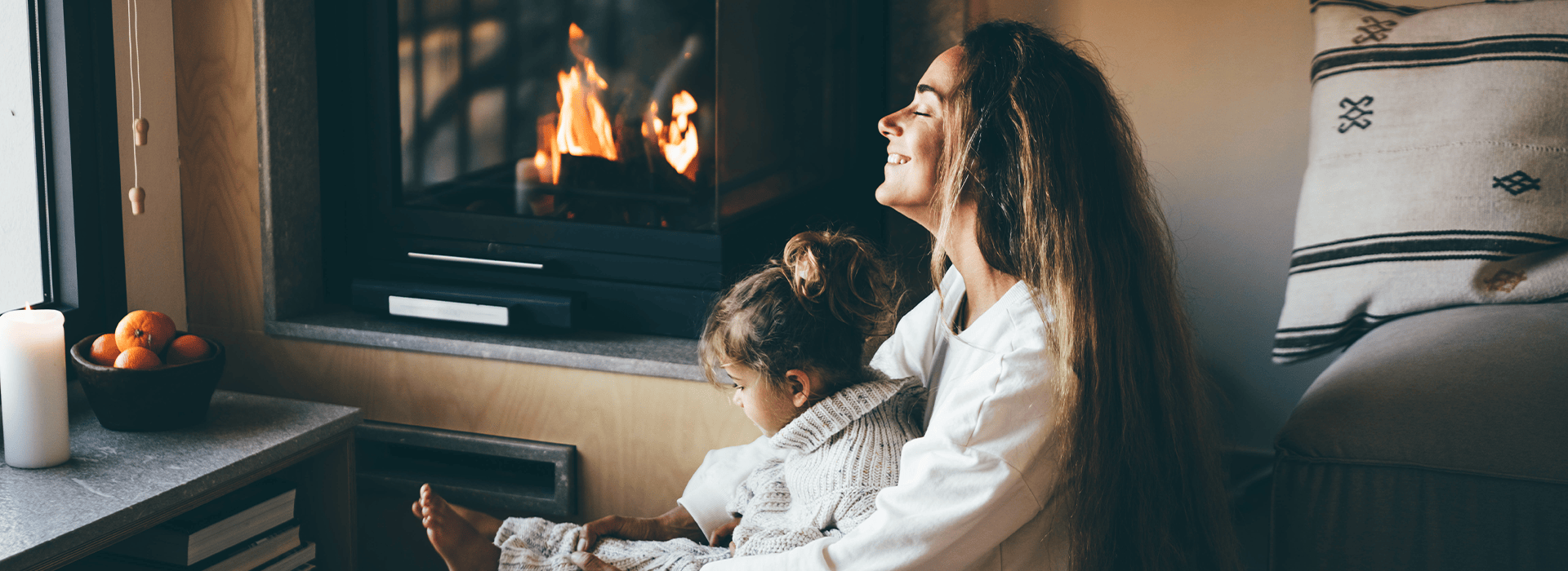 Glückliche Mutter und Tochter ruhen sich zu Hause am Kamin aus.
