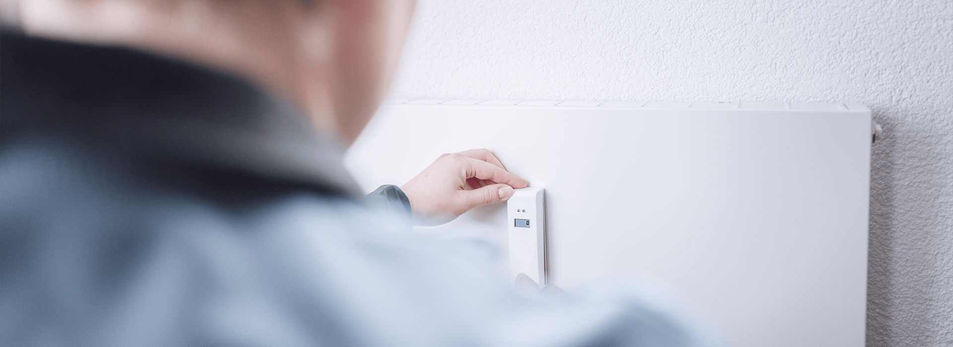 Ein Heizkostenverteiler wird an einer Heizung montiert.