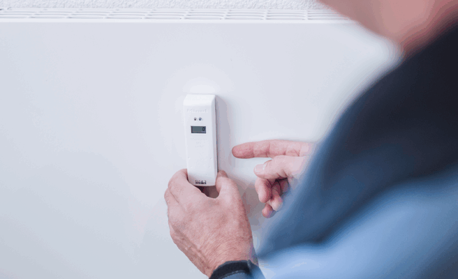 Ein Heizkostenverteiler wird an einer Heizung montiert.