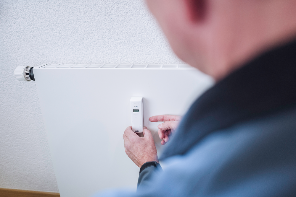 Ein Heizkostenverteiler wird an einer Heizung montiert.