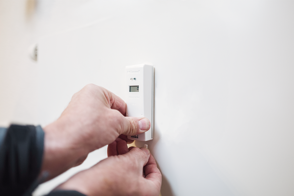 Ein Heizkostenverteiler wird an einer Heizung montiert.