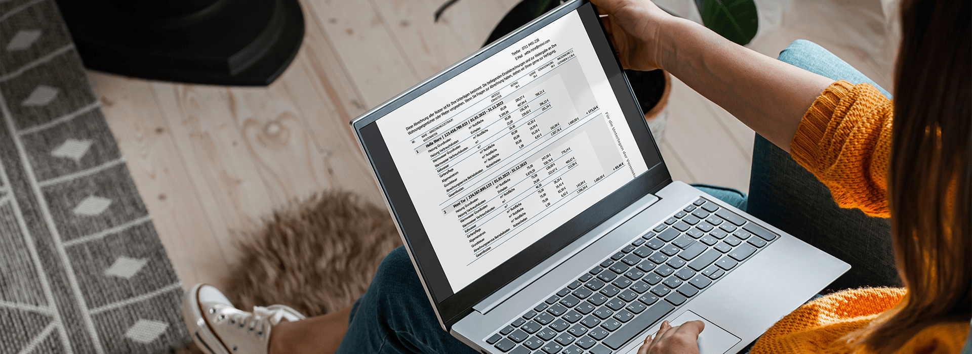 Frau mit Laptop auf dem Schoß schaut sich die Heizkostenabrechnung darauf an.