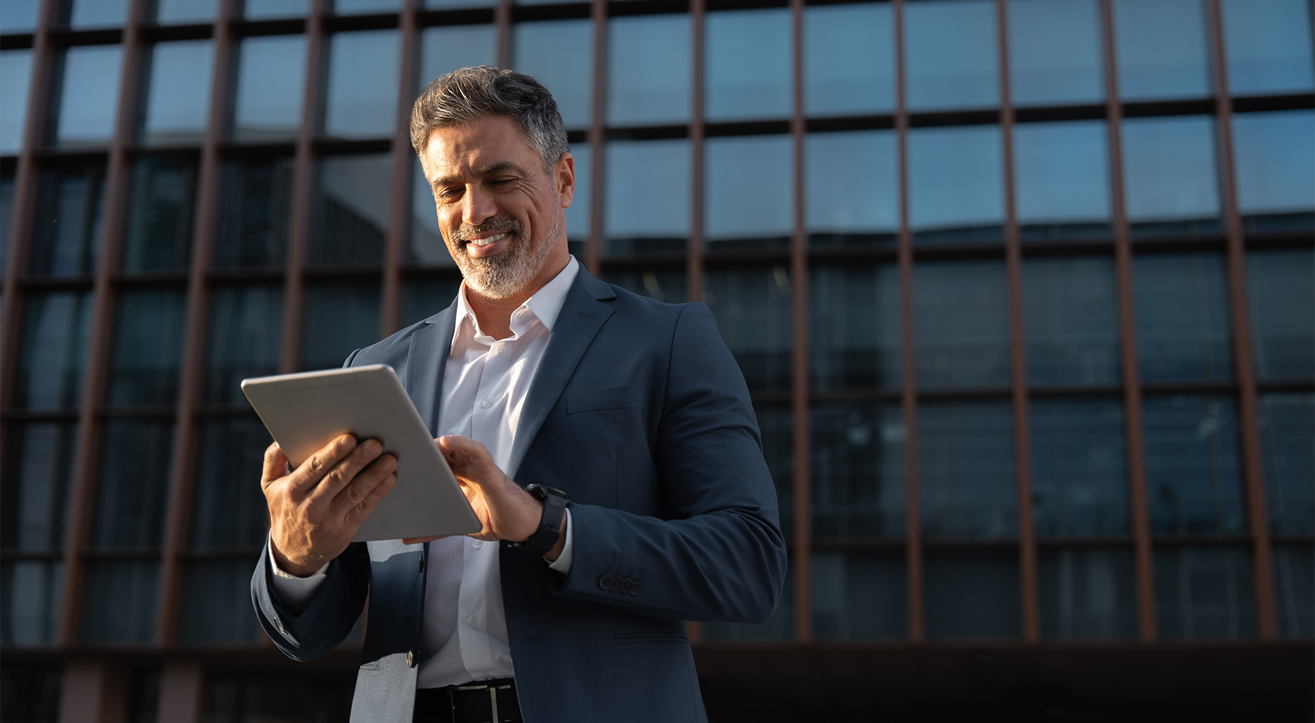 Mann mit einem Tablet steht vor einem Geb&auml;ude